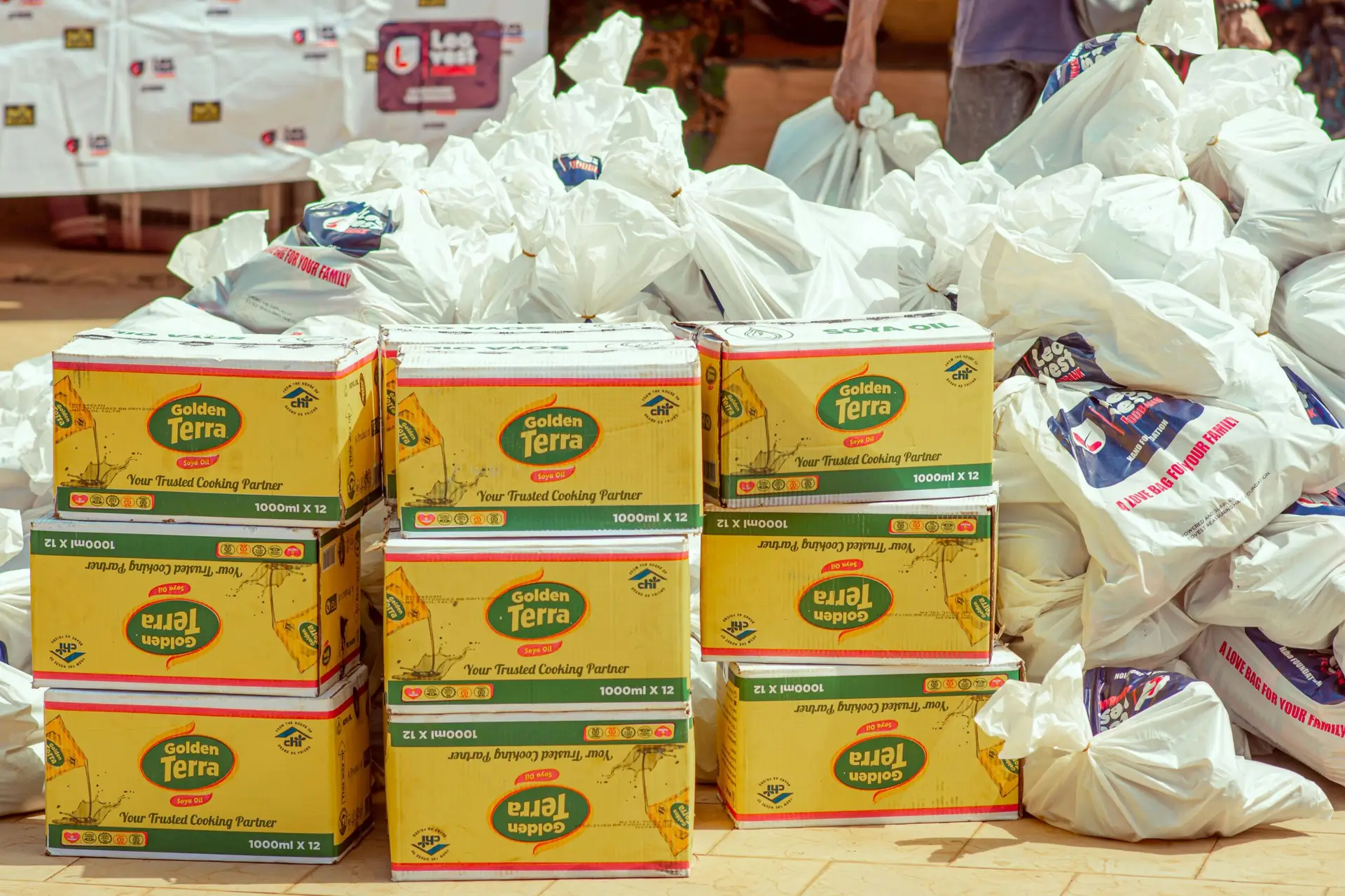Boxes of Golden Terra cooking oil and plastic bags stacked outdoors.